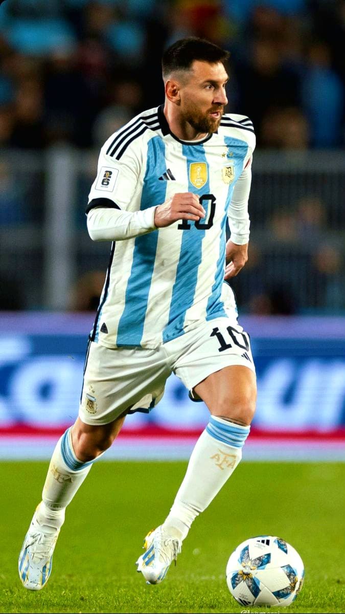 A male soccer player in an Argentina national team uniform, wearing number 10, runs on the field while dribbling a soccer ball during a match broadcasted via IPTV French channels.
